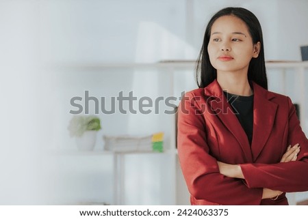 Cute Asian businesswoman in suit in modern workplace. Thai woman. Southeast Asian woman. looking at laptop in office