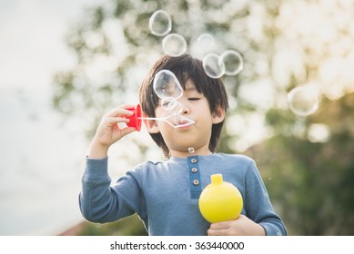 Cute asian child is blowing a soap bubbles