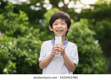 Cute Asian Child  Drinking A Carton Of Milk From A Box With A Straw