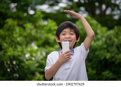 Cute Asian Child  Drinking A Carton Of Milk From A Box With A Straw