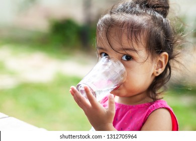 Cute Asian Child Girl Drinking Clear Water Outdoors. Pure Water