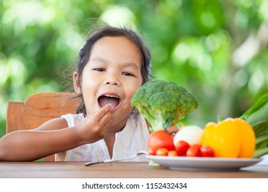 Cute Asian Child Girl Eating Broccoli And Learning About Vegetables With Happiness