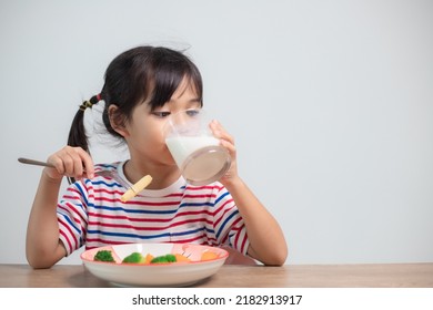 Cute Asian Child Girl Eating Healthy Vegetables And Milk For Her Meal