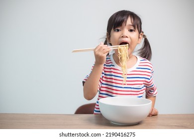 Cute Asian Child Girl Eating Delicious Instant Noodles At Home.