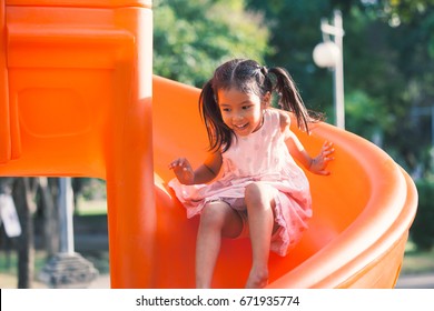 Cute Asian Child Girl Having Fun To Play Slider In The Playground In Summer Time