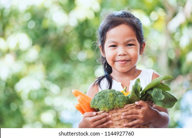 Cute Asian Child Girl Holding Basket Of Vegetables Prepare For Cooking With Her Parent