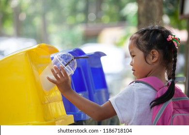 Cute Asian Child Girl Throwing Plastic Glass In Recycling Trash Bin At Public Park