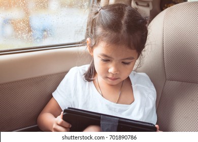 Cute Asian Child Girl Using Smartphone, Tablet In The Car While Raining In Vintage Color Tone