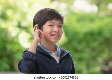 Cute Asian Child With Hearing Aid On Nature Background