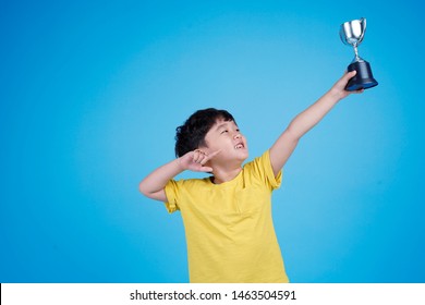 Cute Asian Child Holding Up A Trophy On White Background Isolated