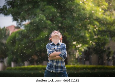 Cute Asian Child Looking Up In The Park Under The Rain