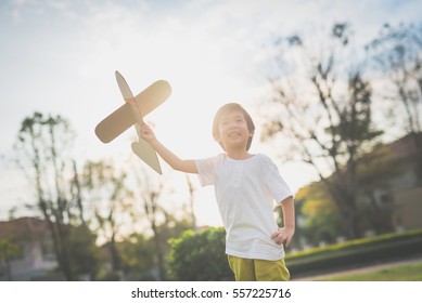 Cute Asian Child Playing Cardboard Airplane In Thee Park Outdoors