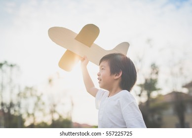 Cute Asian Child Playing Cardboard Airplane In Thee Park Outdoors