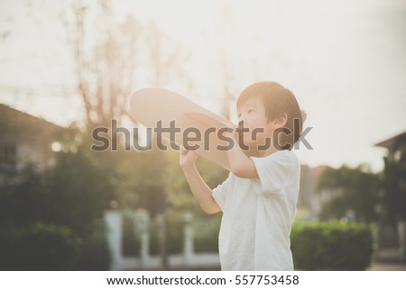 Cute Asian child playing cardboard airplane in thee park outdoors