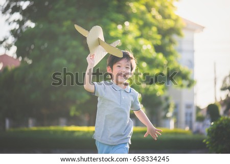 Cute Asian child playing cardboard airplane in the park outdoors