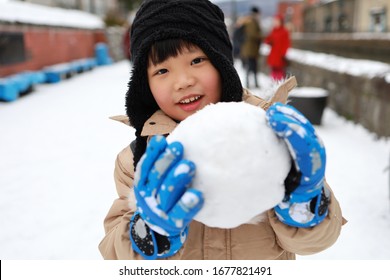 Cute Asian Child Playing On Snow In The Park.