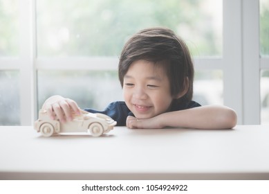 Cute Asian Child Playing Wooden Toy Car On A Table