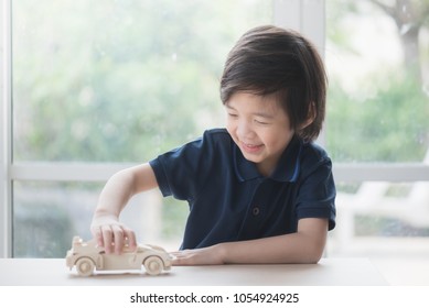 Cute Asian Child Playing Wooden Toy Car On A Table