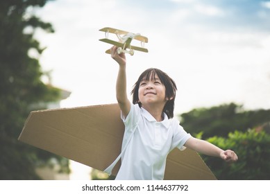 Cute Asian Child Playing Wooden Airplane In The Park Outdoors