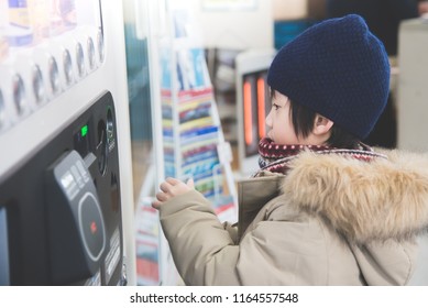 Cute Asian child purchasing soft drink from vending machine in the train station - Shutterstock ID 1164557548