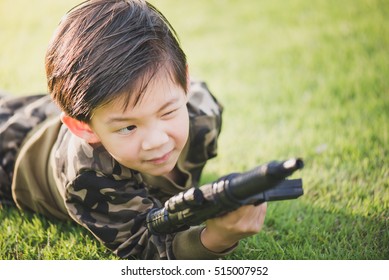 Cute Asian child in soldier uniform playing toy gun outdoors - Shutterstock ID 515007952