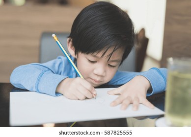 Joli enfant asiatique écrivant sur un livre blanc : photo de stock