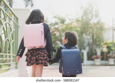 Cute Asian children holding hand together while going to the school outdoors,back to school concept