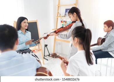 Cute Asian Children Holding Violin On Her Shoulder And Play Violin, She Show Violin Skill And Present Melody And Song To Teacher And Friends, Asian Children Group In Musical Training Time