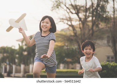 Cute Asian children playing cardboard airplane together in the park outdoors - Powered by Shutterstock