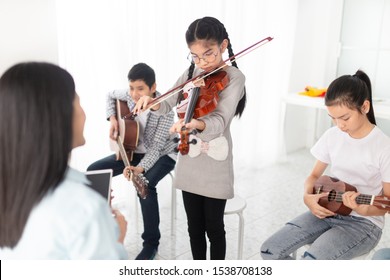 Cute Asian Children Playing Violin With. Friends, She Show Violin Skill And Present Melody And Song To Teacher And Friends, Asian Children Group In Musical Training Time