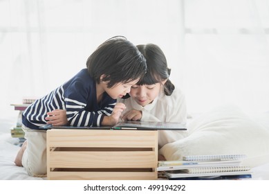 Cute Asian Children Reading A Book On White Bed