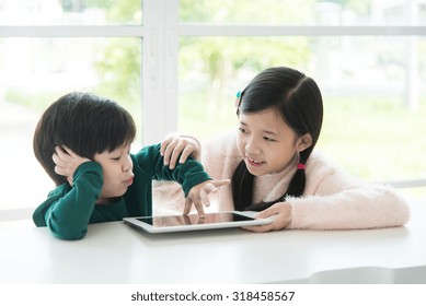 Beaux enfants asiatiques utilisant une tablette sur une table blanche : photo de stock
