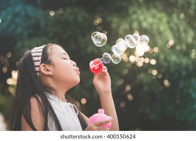 かわいいアジアの女の子が石けんの泡を吹いている、ビンテージフィルターの写真素材