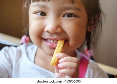 Cute Asian Girl Happy Eating French Fries.
