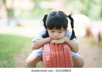 Cute asian girl resting sitting after play on school or kindergarten yard or playground. Healthy activity for children. Little girl vacant outdoors at playground. Child playing on outdoor playground.