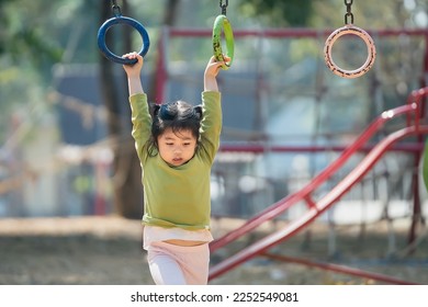 Cute asian girl smile play climb the bar on school or kindergarten yard or playground. Healthy activity children. Little girl climbing outdoors at playground. Child playing on outdoor playground. - Powered by Shutterstock