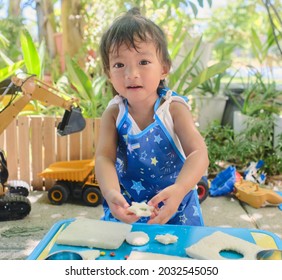 Cute Asian Girl Wearing Apron Having Fun Preparing Sandwiches, Little Kid Making Cookie Cutter Sandwiches At Home Backyard On Nature, Cooking With Kids, Fun Outdoor Activities For Preschool Concept