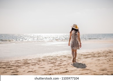Cute Asian girl in white dress walking on the beach