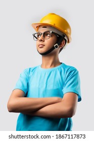 Cute Asian Indian happy kid wearing yellow construction helmet or safety hard hat, standing isolated on white background holding blueprint