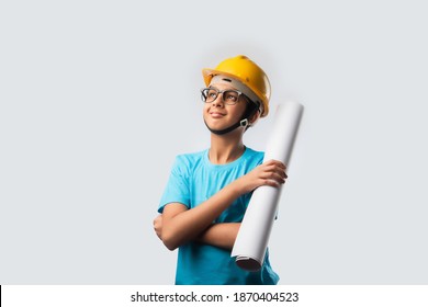 Cute Asian Indian happy kid wearing yellow construction helmet or safety hard hat, standing isolated on white background holding blueprint