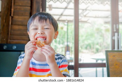 Cute Asian Kid Boy Eating Fried Chicken By Self. Copy Space. Soft Focus.