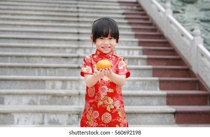 Cute asian kid girl in Traditional Chinese dress with holding sacred Orange at chinese temple in bangkok thailand, Chinese new year concept.