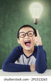 Cute Asian little boy wearing a round glasses and pointing at a bright light bulb - Shutterstock ID 291513263