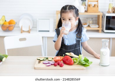 Cute Asian Little Child Girl Drinking Milk In The Kitchen 