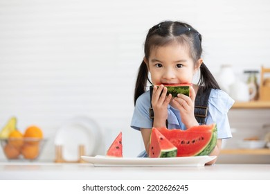 Cute Asian Little Child Girl Eating Slice Watermelon In The Kitchen