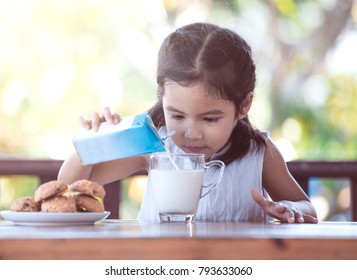 Cute Asian Little Child Girl Pouring Milk Into Glass For Breakfast