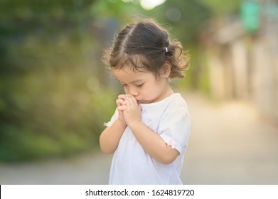 Cute asian little girl closed her eyes and praying in the morning. Little asian girl hand praying,Hands folded in prayer concept for faith,spirituality and religion.