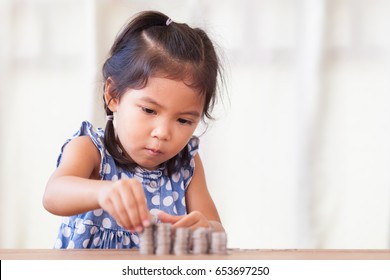 Cute Asian Little Girl Playing With Coins Making Stacks Of Money,kid Saving Money For The Future Concept