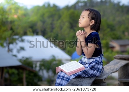 Cute asian little girl read bible and pray in morning with copy space, christian concept.