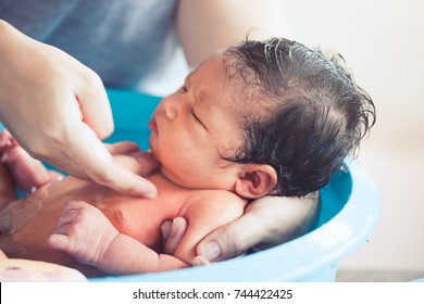 Cute Asian Newborn Baby Girl Take A Bath In Bathtub. Mom Cleaning Her Baby Body With Tenderness